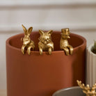 Three gold animal figurines on a brown cylindrical container with a blurred background