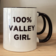  White ceramic  mug with black handle and black trim at top. Bold font 100% Valley Girl. Design on both sides